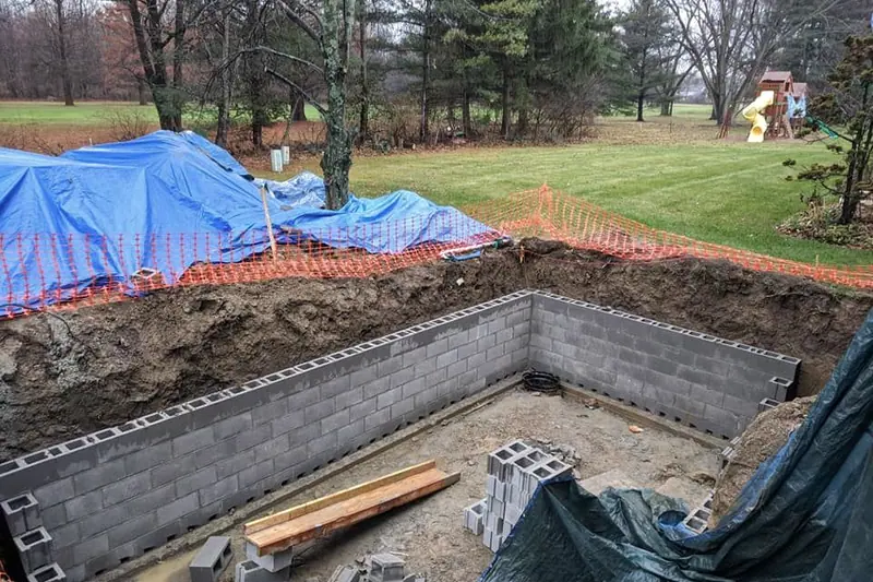 New concrete block foundation for a room addition in a wooded backyard