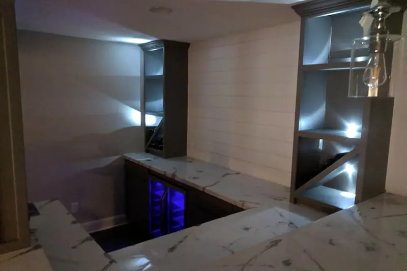 Basement bar at night with lit open shelving