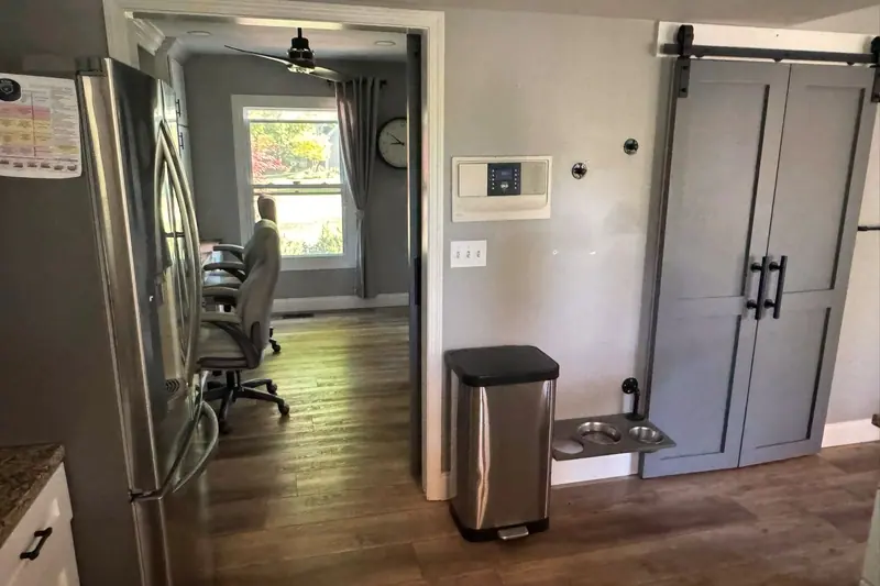Gray sliding barn-door pantry beside a stainless refrigerator