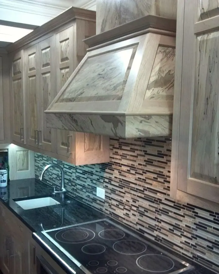 Weathered wood range hood and cabinets above mosaic glass tile